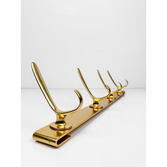 Charming mid-20th century wall coat rack made of gilt metal. Featuring four double hooks mounted on a bar that curves at...