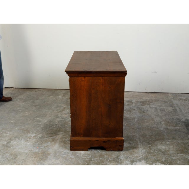 An English Georgian period oak chest from the early 19th century, with four drawers and carved motifs. Created in England...