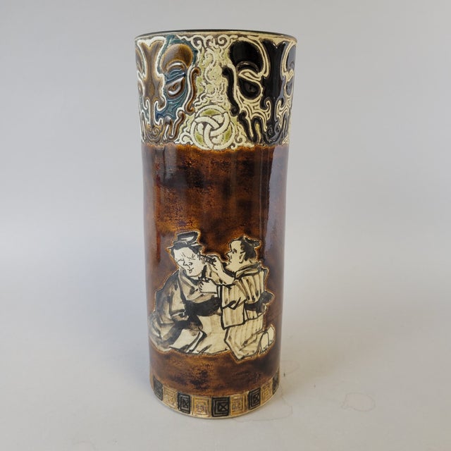 A Japanese stoneware brush pot dating to the Meiji period (circa 1890–1915), decorated with two humorous domestic scenes...