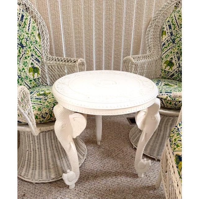 Hand-carved solid wood round accent side end table featuring three sculptural elephant head supports with elongated trunks...