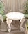 Hand-carved solid wood round accent side end table featuring three sculptural elephant head supports with elongated trunks...