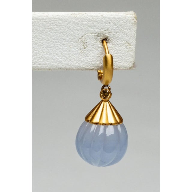 An unusual pair of drop earrings with a hoop-style fastener. They feature carved chalcedony gemstones with a melon-shape...