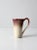 This vintage studio pottery mug is a weighty, hand-crafted ceramic piece with a creamy white glaze accented by a rich...