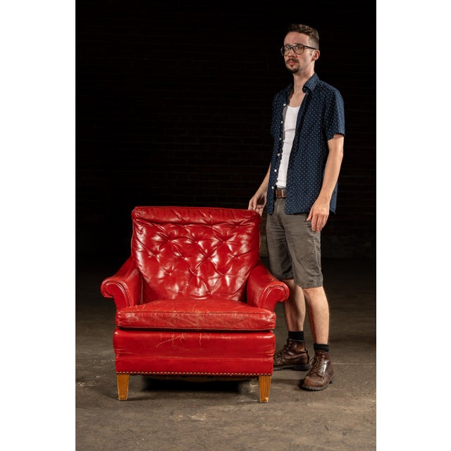 Striking lounge chair in bold red leather upholstery, featuring a tufted back cushion with deep buttoning and a wide,...