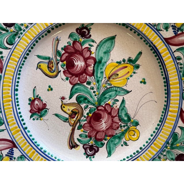 Striking large Italian maiolica charger featuring vibrant hand-painted florals, scrolling foliage, and bird motifs in rich...