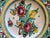 Striking large Italian maiolica charger featuring vibrant hand-painted florals, scrolling foliage, and bird motifs in rich...