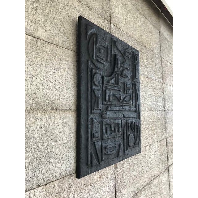 Hieroglyph-like patterns are sculpted and layered to create depth and texture. The plaster surface has been finished in a...