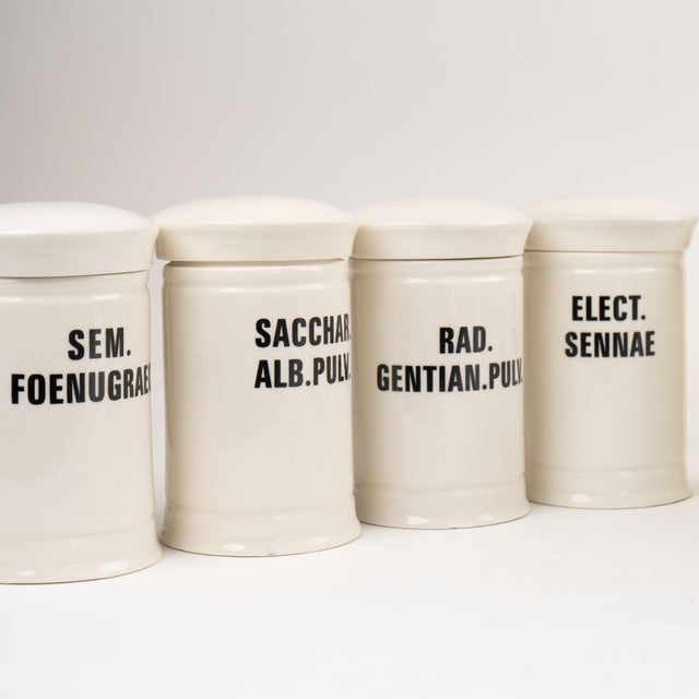 Charming antique-inspired ceramic apothecary jar featuring classic off-white glazing with elegant black vintage font...