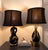 A striking companion pair of vintage sculptural ceramic table lamps in glossy black glaze with warm gilt accents and...