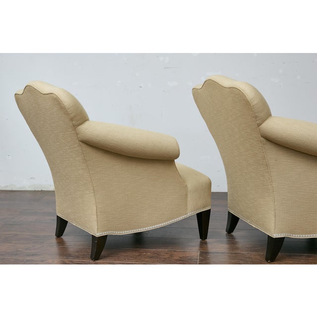 A vintage pair of French lounge chairs with rolled arms, camelbacks, ebonized legs and upholstery. This vintage pair of...