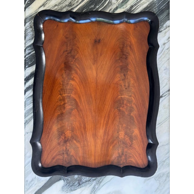 Presenting an antique hand carved flame mahogany serving tray. The frame is stained black with plenty of curves and...