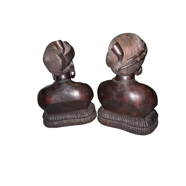 An exceptional and striking pair of mid-century, hand-carved solid hardwood bust statues depicting a man and a woman....