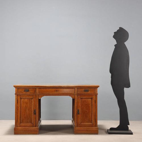 Oak desk. Top with black leather insert, three drawers in the lower section, and doors in the side panels. Handles and...