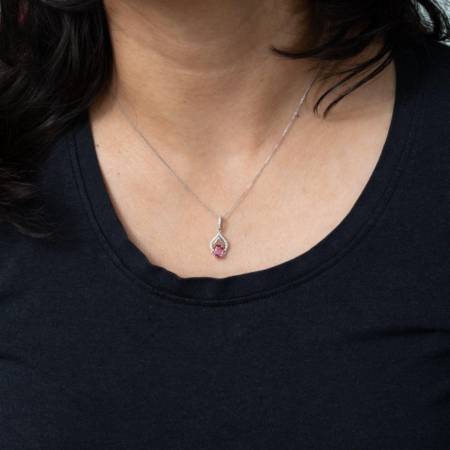 A 0.83-carat padparadscha sapphire in an oval cut anchors this solid 14K white gold pendant, lined with twenty-five earth-...