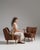 This pair of 1940s Mid-Century Modern upholstered armchairs from Denmark, covered in warm brown bouclé with slim, honey-...