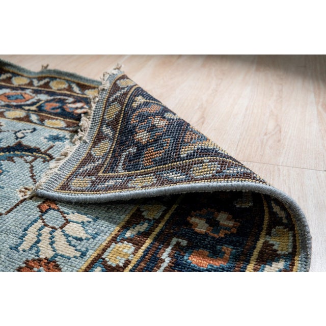A hand-knotted wool rug, made in India and measuring 9' x 12'. Floral drawing carried across the field inside a...