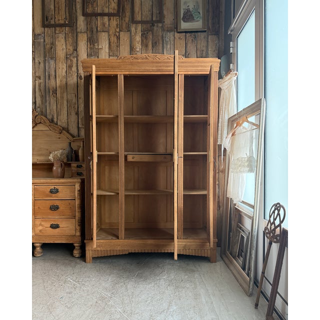 This large art deco oak wardrobe dates from the 1930s. Its three doors, central beveled mirror, and geometric and floral...