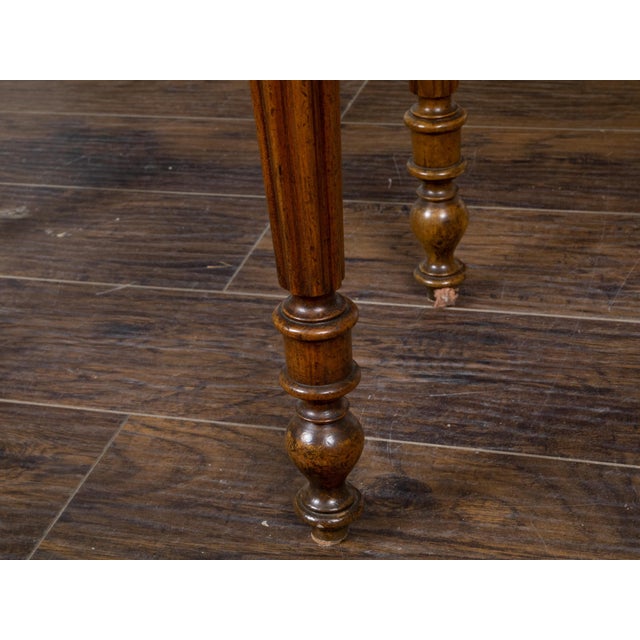 A French walnut side table from the 19th century, with tray top, six drawers, carved apron and four fluted legs. Created...
