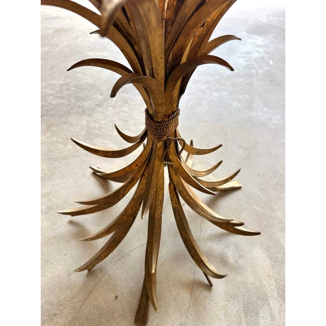 Small gilt metal side table with a wheat sheaf motif. The "Coco Chanel" model, attributed to Robert Gossens. Clear glass...