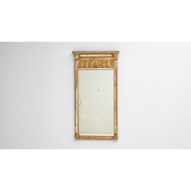 This early 20th-century French wooden mirror features an elegant carved and gilded frame highlighted by a detailed frieze...