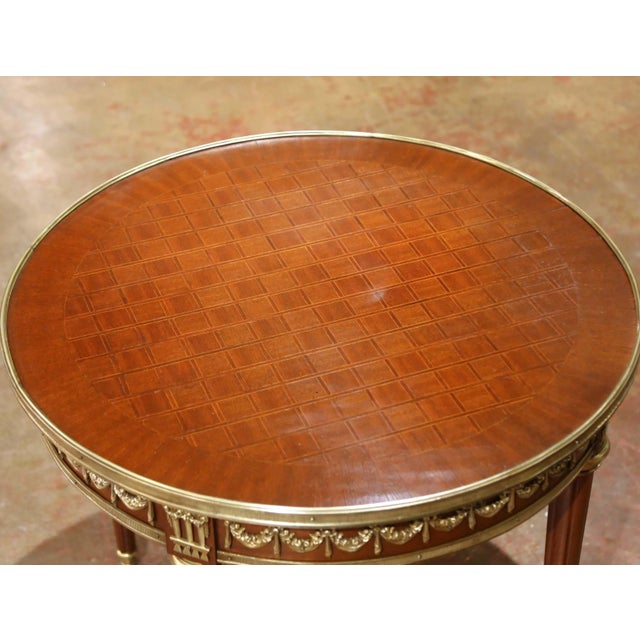With its finely detailed marquetry top and richly ornamented gilt bronze mounts, this antique French Louis XVI style...