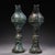 This is a matching pair of cast bronze stemmed cups, each featuring a bulbous upper body that tapers into a slender stem...