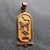 An 18 karat (18K) yellow gold charm pendant designed as an elongated rectangular tablet with Egyptian heiroglyphics....