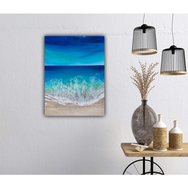 This mixed media artwork depicts the dynamic interplay of ocean waves meeting a sandy shore, rendered in vibrant shades of...