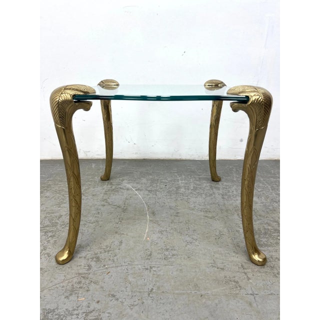Rare vintage side table in the style of P.E. Guerin, featuring sculpted frond-style legs and a thick round glass top. The...