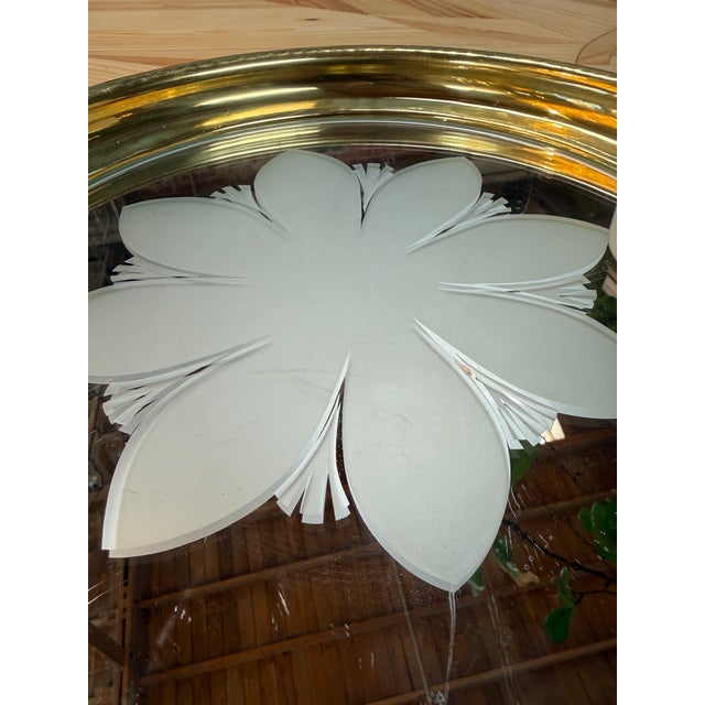 An elegant round tray featuring a broad brass rim with a hammered texture and a mirrored glass center decorated with a...