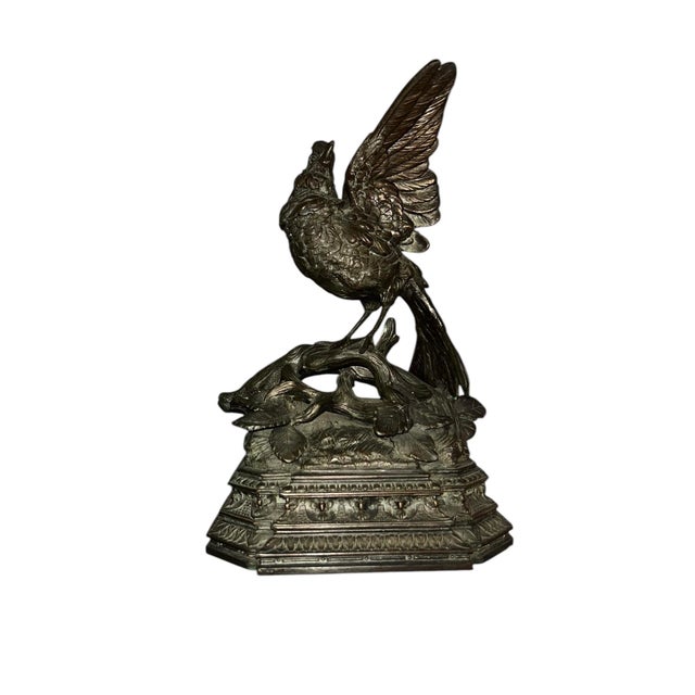 This vintage cast‑metal bird sculpture features a finely modeled bird with partially raised wings perched on a textured...