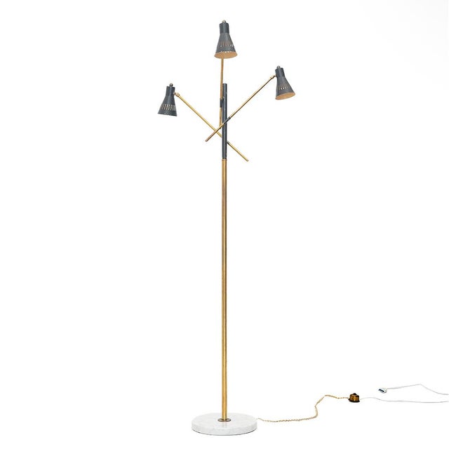 Floor lamp of Italian manufacture produced in the 1950s. Round white marble base. Stem and three arms in brass and black...