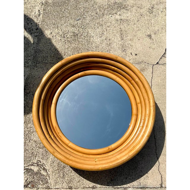 This striking mirror features a series of thick, concentric rings of hand-formed bent rattan that create a deep,...