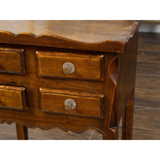 A French walnut side table from the early 20th century, with carved tray top and four small drawers. Created in France...