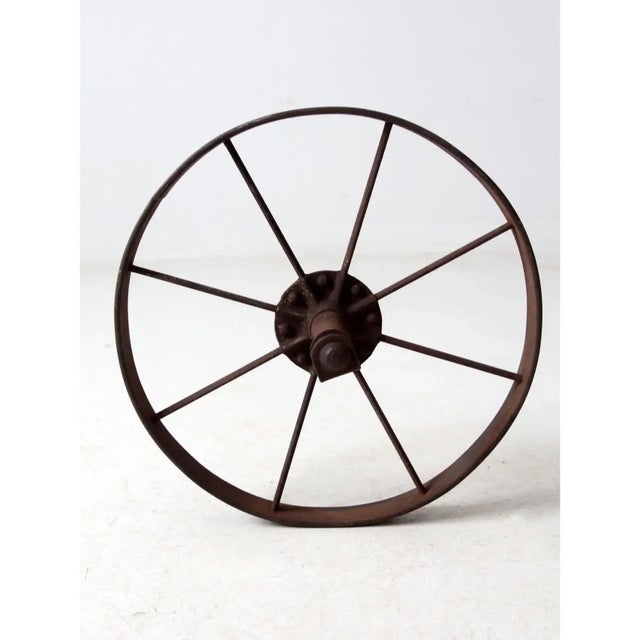 This antique iron wheel features solid construction with a narrow profile and mounted hubs, highlighting its industrial...