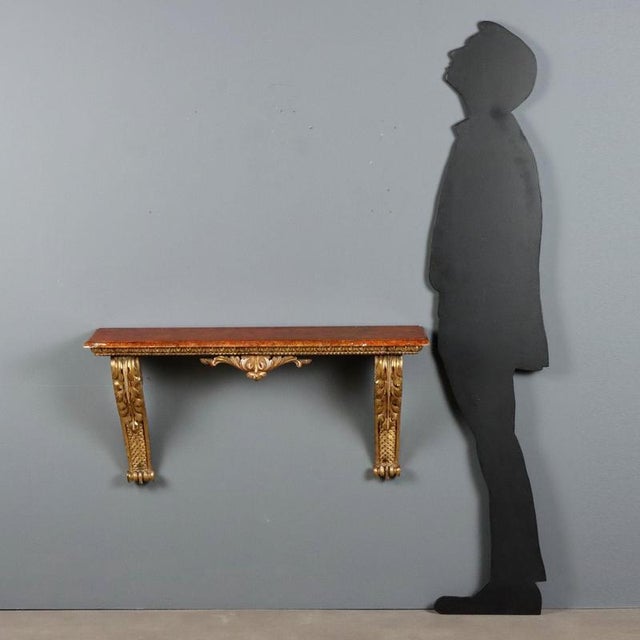 Small carved and gilded wood console from the 19th century, of Italian craftsmanship. The top, featuring a faux marble...