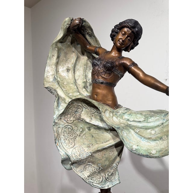 A dramatic large-scale decorative sculpture depicting an exotic dancer in motion, presented with a substantial...