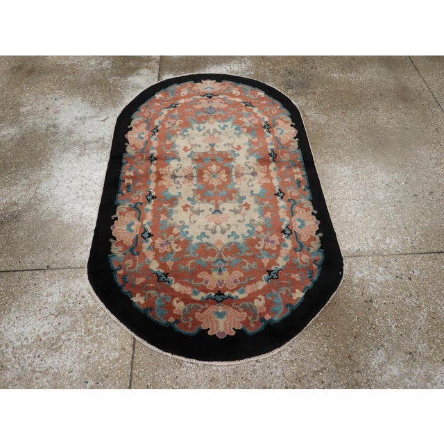 This mid-20th century Chinese Art Deco rug, features a richly detailed design with a distinctive oval shape. The intricate...