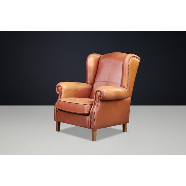 Impressive cognac leather wingback lounge chair, originating from The Netherlands and dating from the 1960s, upholstered...