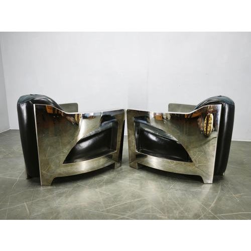 An impressive pair of Timothy Oulton Aviator armchairs, expertly combining polished and brushed steel with premium black...