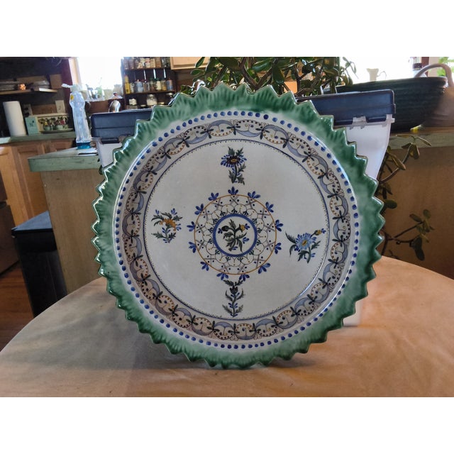 This is a large (12.5 inches) Portuguese ceramic plate featuring a hand carved green saw tooth edge and holes in the back...
