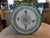 This is a large (12.5 inches) Portuguese ceramic plate featuring a hand carved green saw tooth edge and holes in the back...