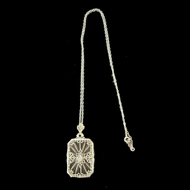 A fine Art Deco period 10K White gold filigree pendant with rock crystal and a small diamond in the center. The pendant...