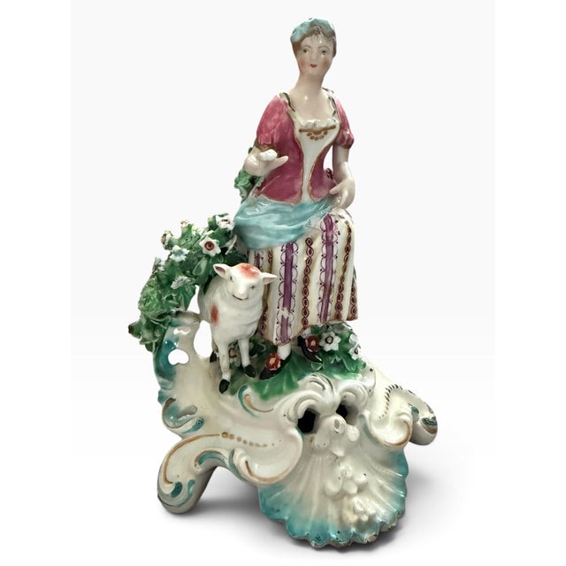 Beautiful antique porcelain pastoral figure depicting a charming shepherdess with a lamb, surrounded by an elaborate...