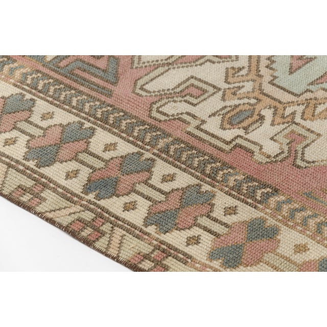 This is a vintage Turkish Oushak rug from the Mid 20th Century. The piece was hand-knotted.