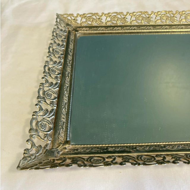 This elegant vintage vanity mirror tray features a beautifully detailed rose filigree metal edging and a clear glass...