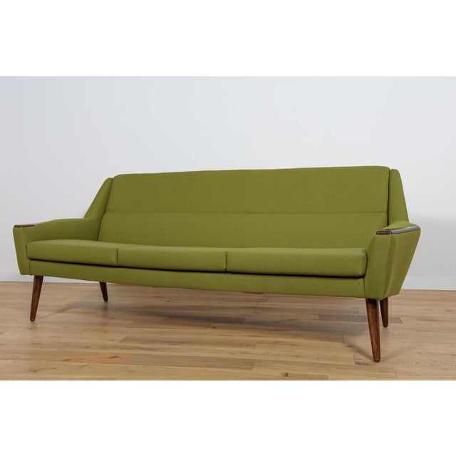 A sofa with a unique contoured shape, produced in Denmark in the 1960s. The sofa has wood armrests from teak wood....