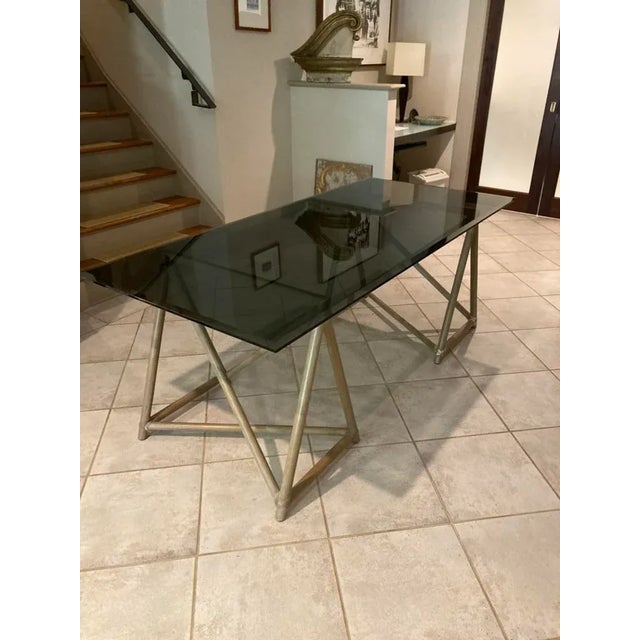 A beveled smoked glass top sits upon a pair of intricate geometric trestles.