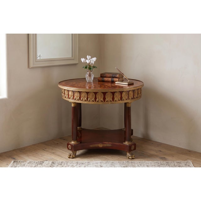 A masterclass in Neoclassical elegance, this Empire-style round table is crafted from rich, deep mahogany and serves as a...