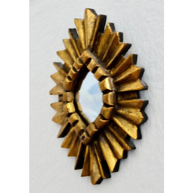 Lovely carved giltwood accent mirror with a sunburst frame. This pretty mirror is perfect to display above and highlight a...